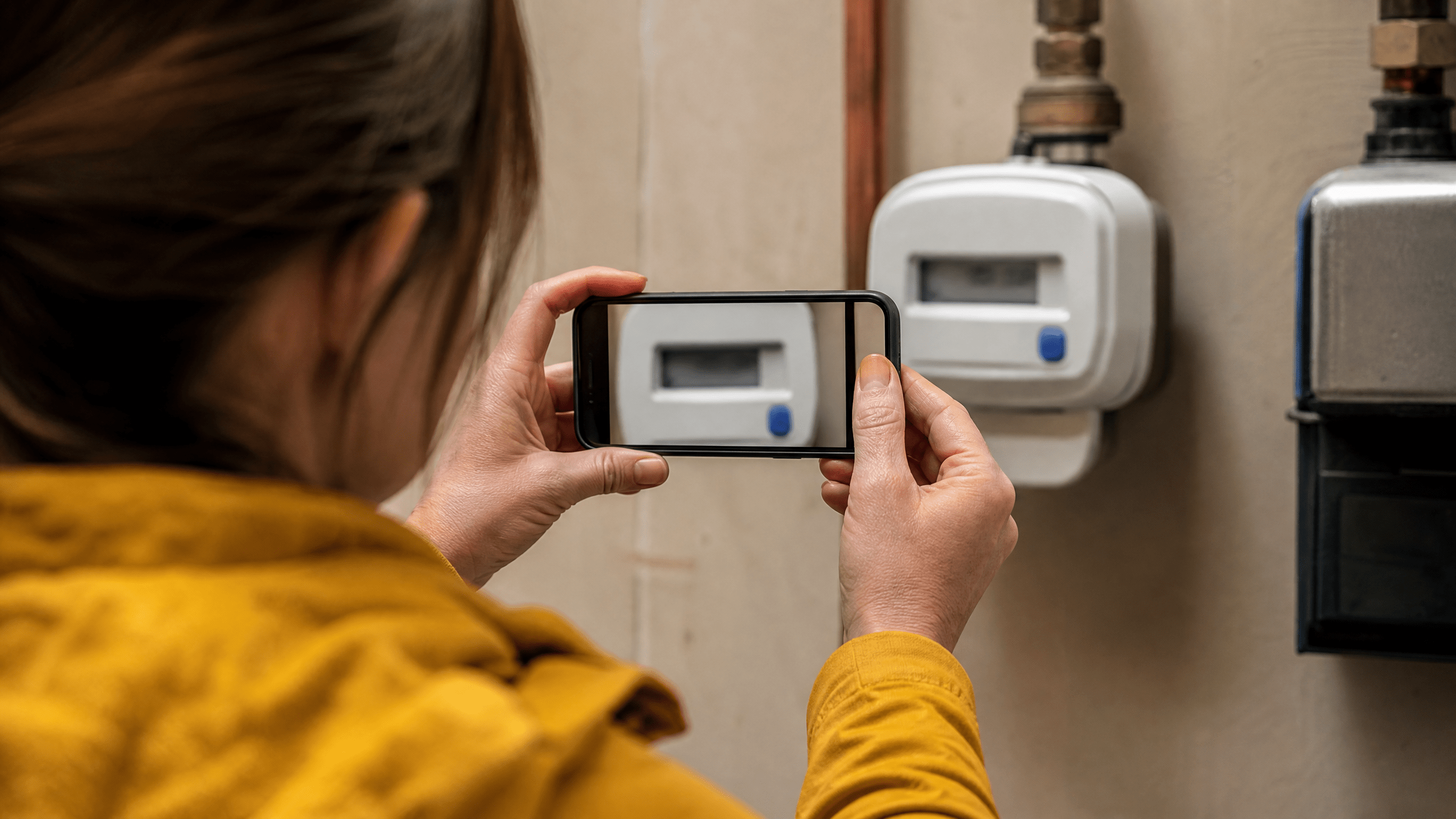 Person fotografiert einen bewusst unleserlichen Zählerstand mit dem Smartphone. Person fotografiert einen bewusst unleserlichen Zählerstand mit dem Smartphone.