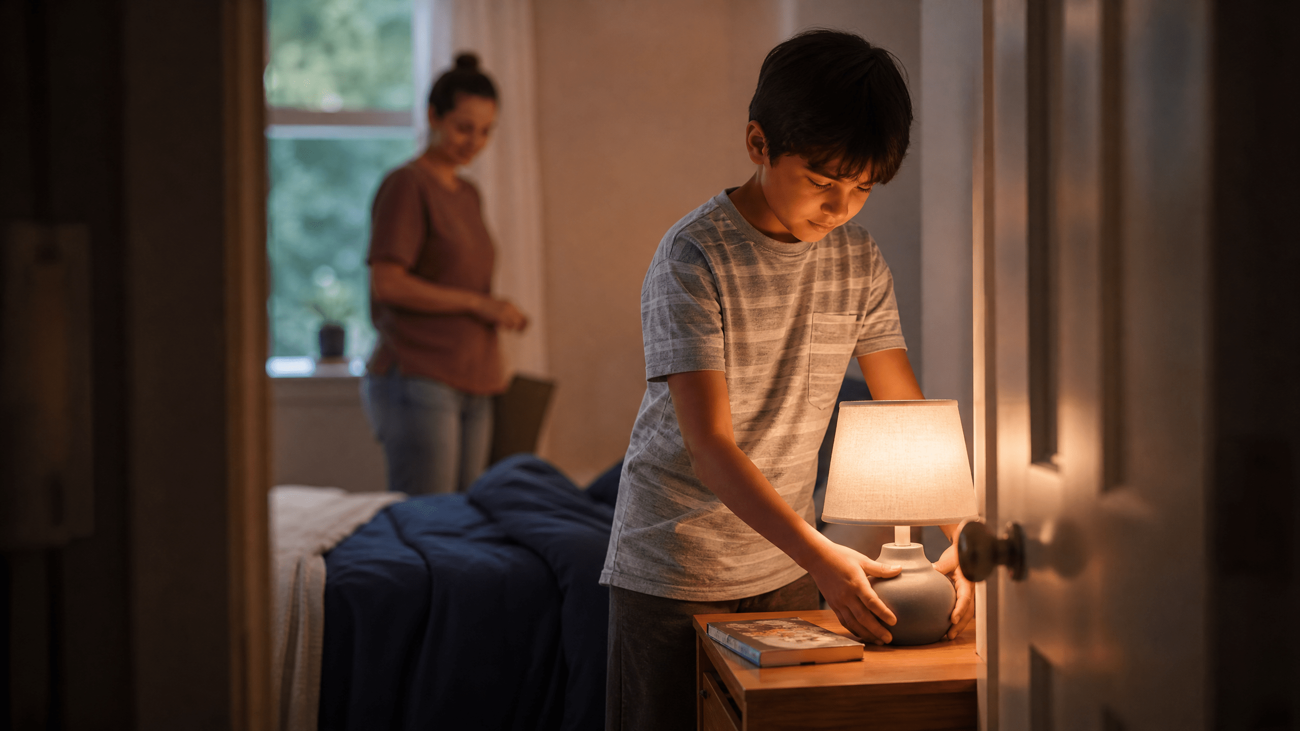 Kind richtet mit Begleitung eine Lampe und ein Buch im neuen Zimmer ein.