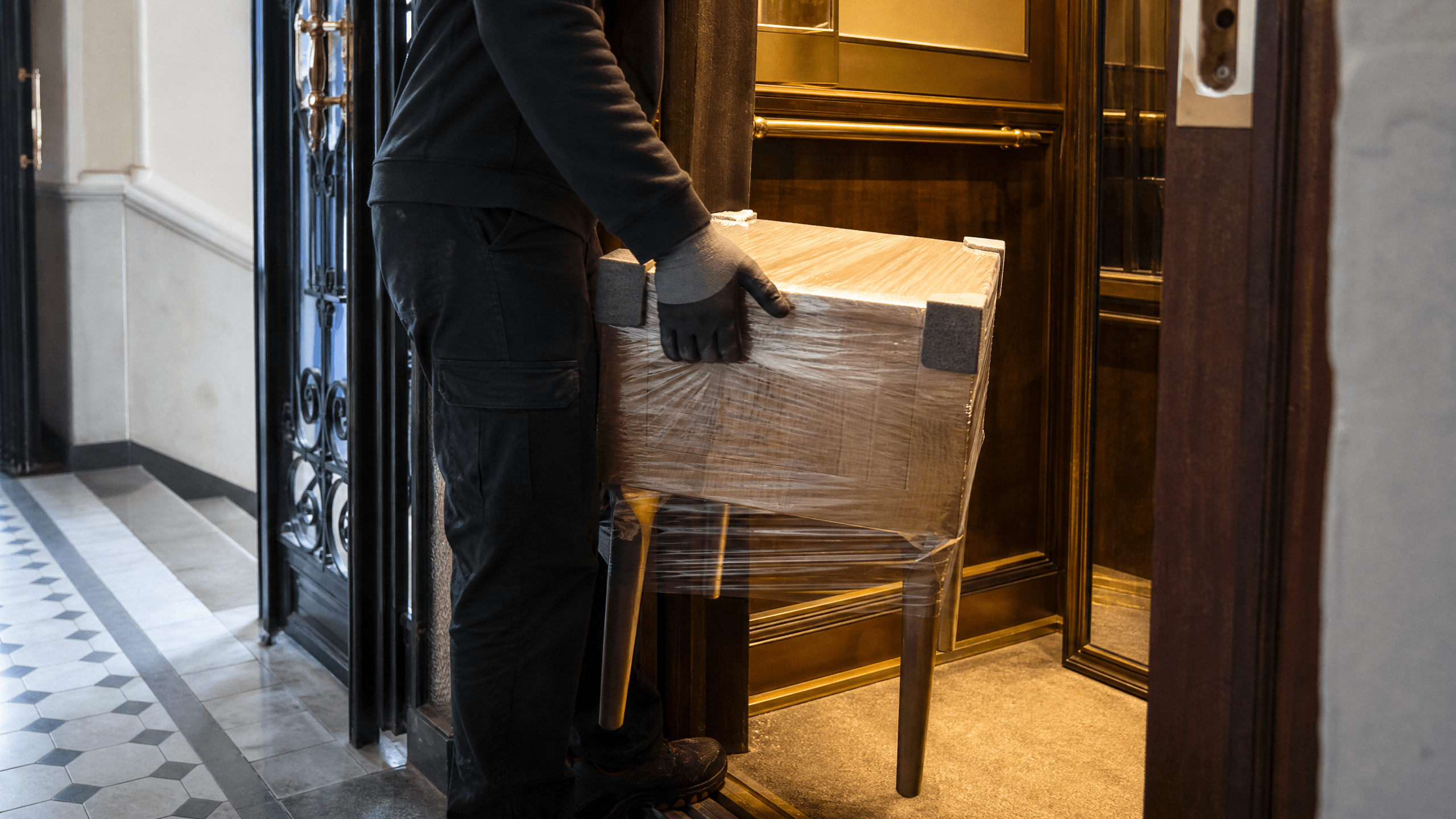Geschützter kleiner Tisch wird vorsichtig in einen historischen Aufzug gestellt.
