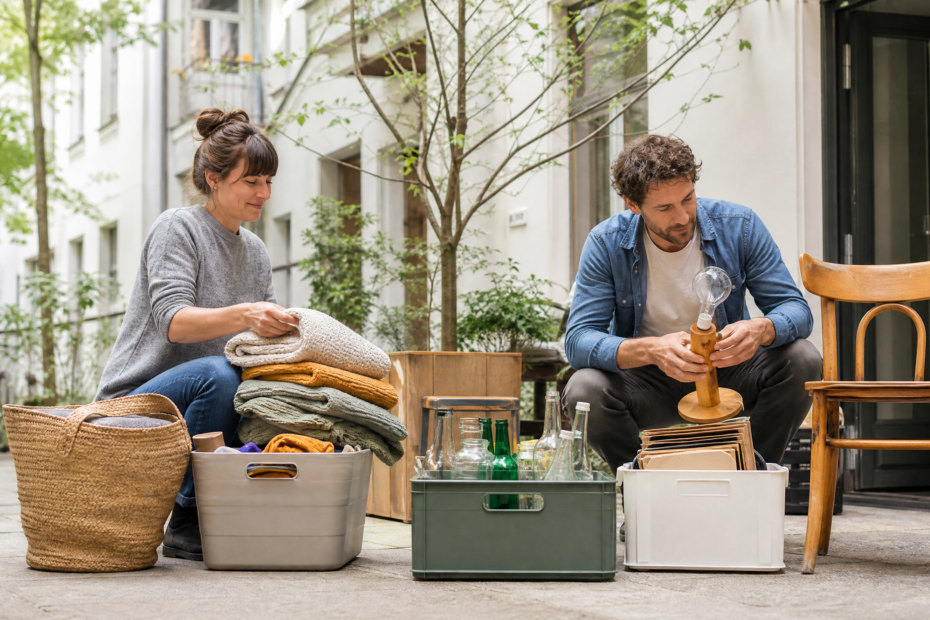 Menschen sortieren gut erhaltene Haushaltsgegenstände in einem sauberen Berliner Innenhof für Wiederverwendung und Recycling.