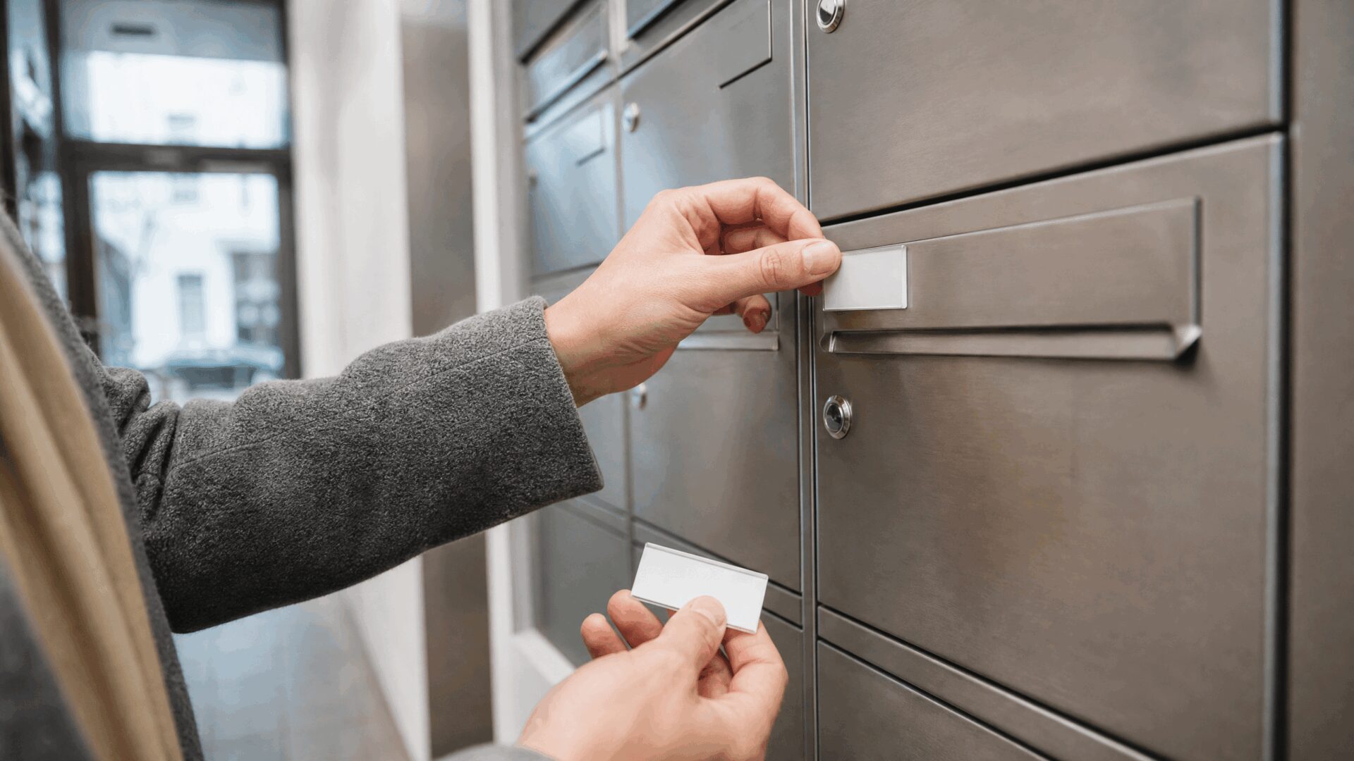 Person erneuert den Namenseinleger an einem modernen Briefkasten